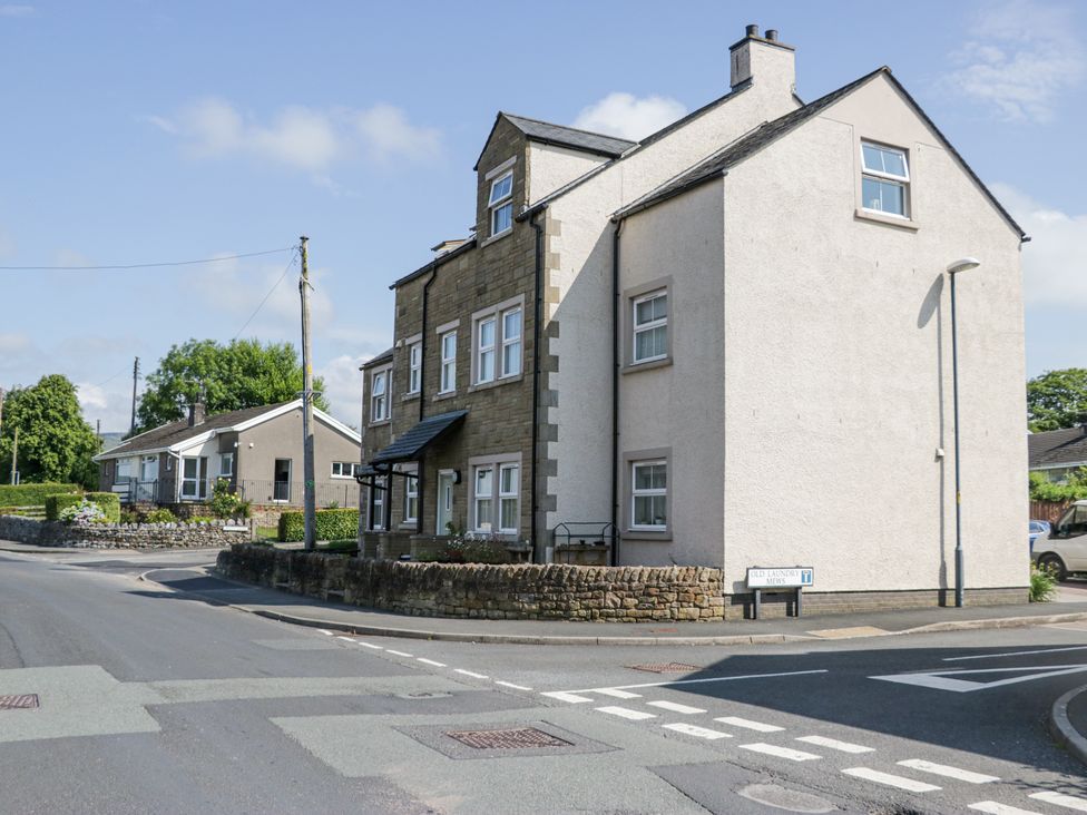 A junction with a stone house and a street sign for Old Laundry Mews in Ingle View Ingleton