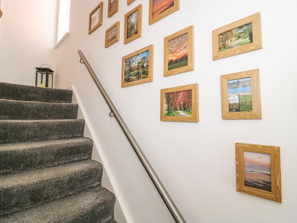 Carpeted staircase with metal handrail and framed pictures on the wall at The Whyte Retreat in Hornsea