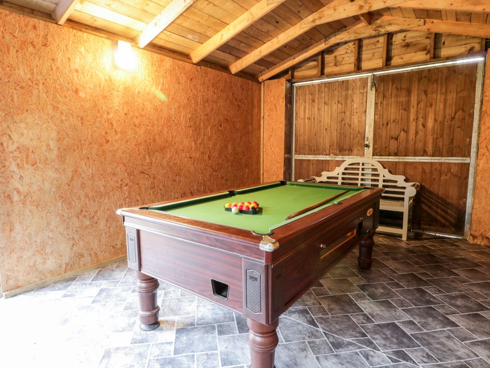 A room with a pool table and a white bench against a wooden wall at Oakbank in Carrutherstown near Annan