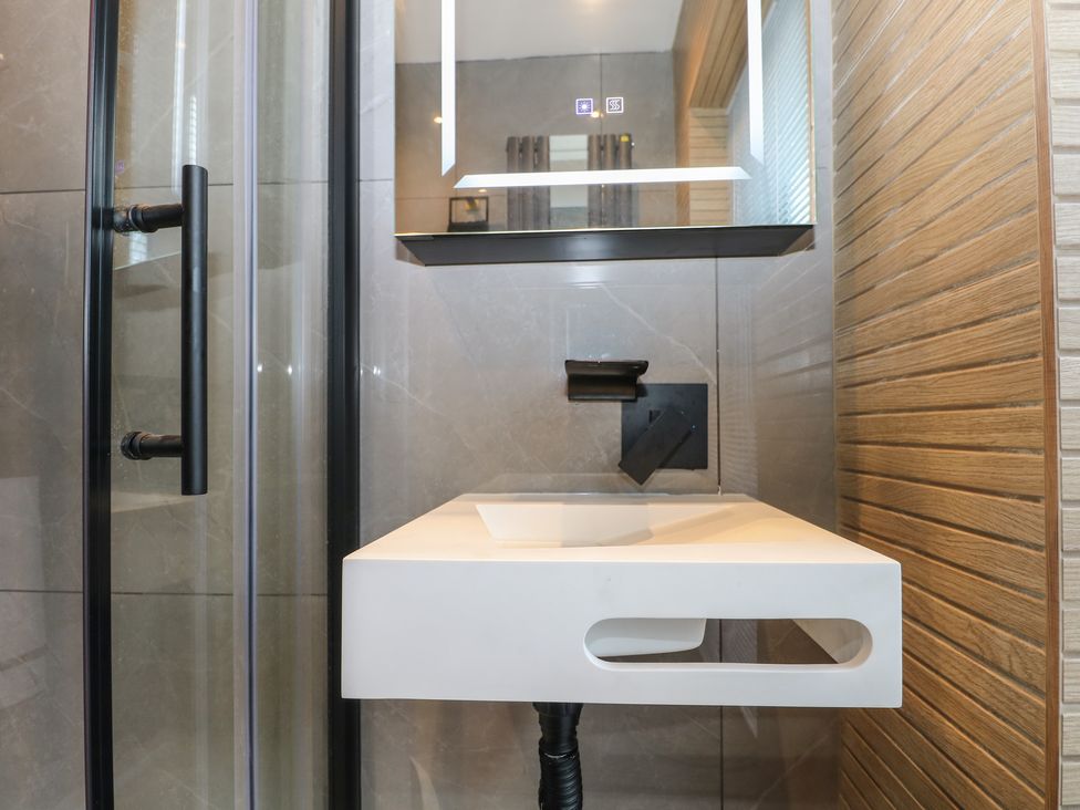 A small bathroom sink with a black faucet and shower door with black handle at Beach Retreat in Seaford