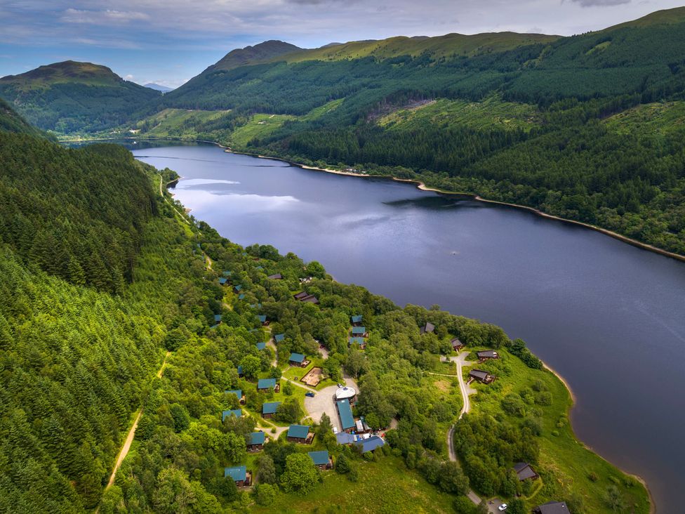 A lake surrounded by forested hills and small buildings at Strathyre Golden Oak Hideaway Strathyre Ben Ledi