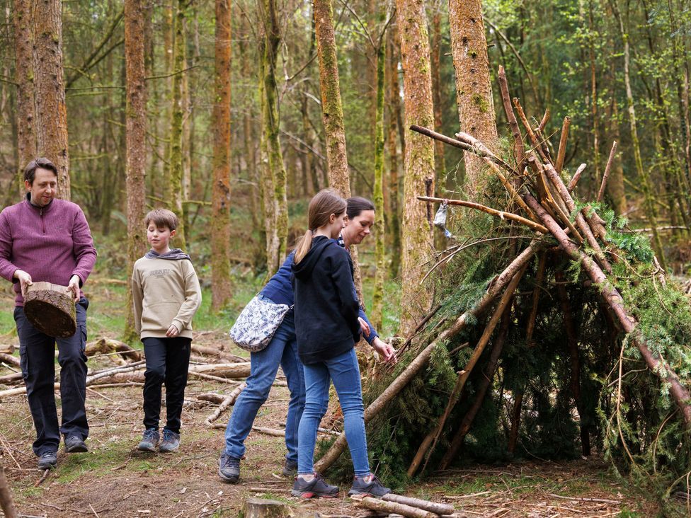 Four people building a shelter with sticks and branches in a forest at Ardgartan Argyll Golden Oak in Ardgartan Loch Long
