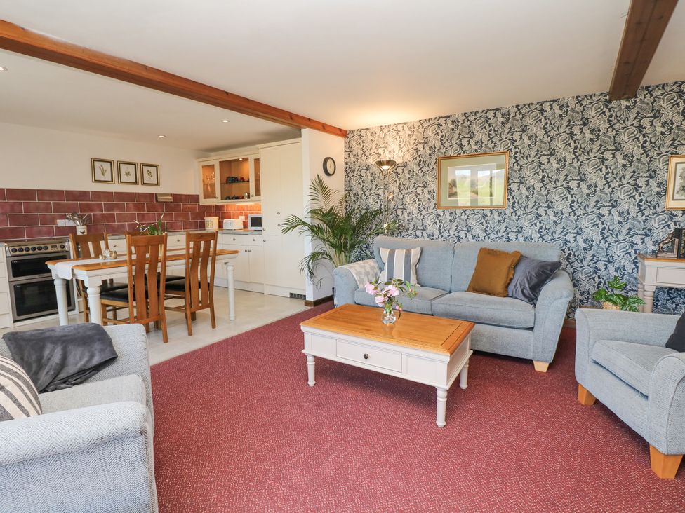 A living room with gray sofas a wooden coffee table and a dining table with chairs at Woodland View in Muddiford near West Down