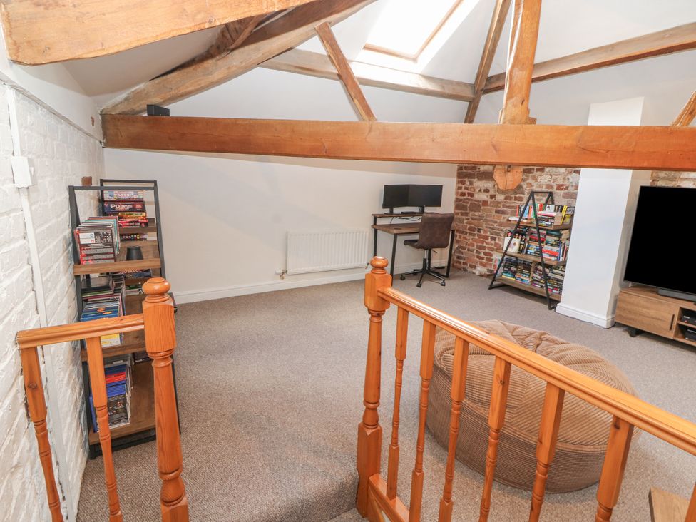 A room with wooden beams a desk with a computer bookshelves a bean bag and a television at The Hideaway @ Waverton Villa in Wigton