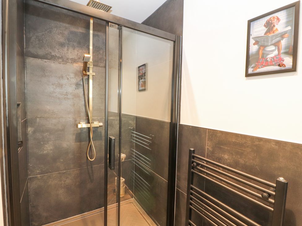 A shower area with glass doors and a black towel radiator in a bathroom with a dog picture on the wall at The Hideaway @ Waverton Villa in Wigton