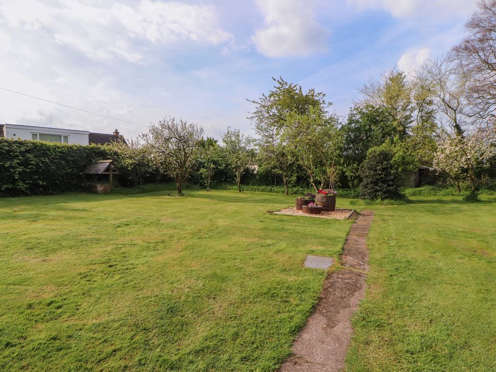 A garden with grass, trees, a path, and flower pots at The Hideaway @ Waverton Villa in Wigton