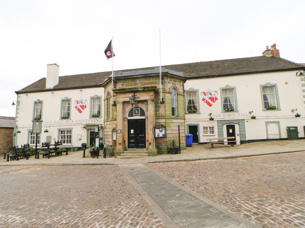 The exterior of a historic building with signs for the town hall pub and dining and the town hall with benches and a cobblestone courtyard at 10 Poppy Lodge in Tunstall near Catterick North Yorkshire