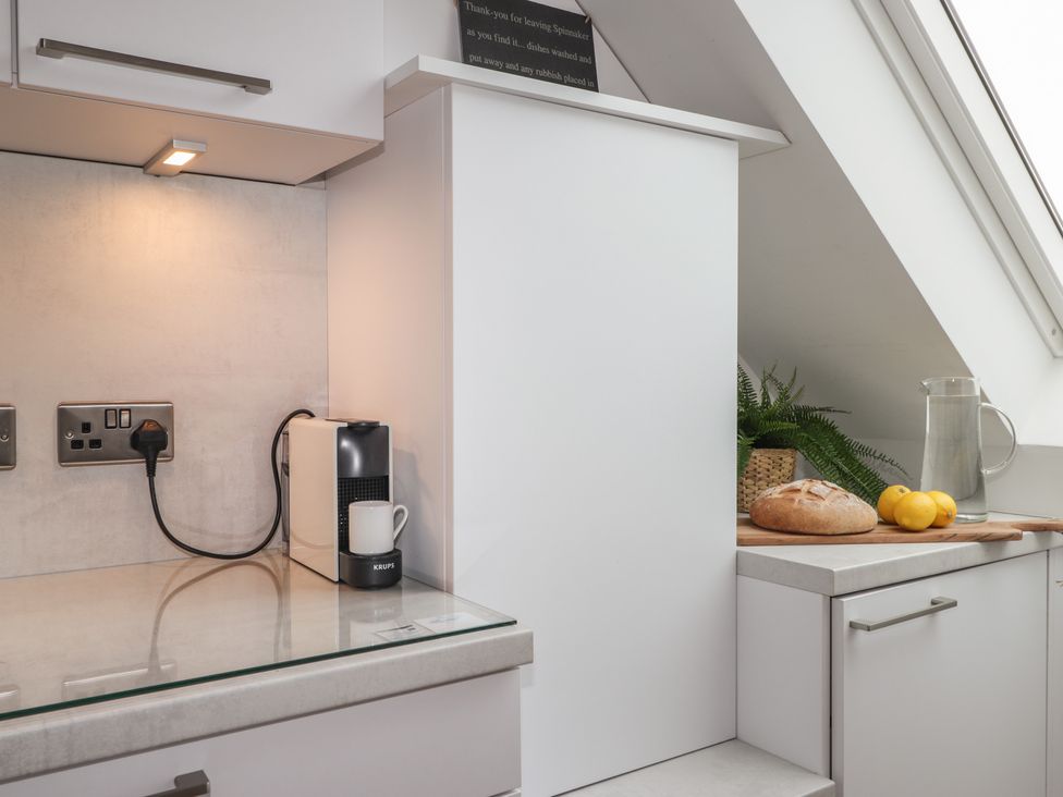 A kitchen counter with a coffee machine a loof of bread lemons a plant and a glass jug of water at Spinnaker in Lossiemouth