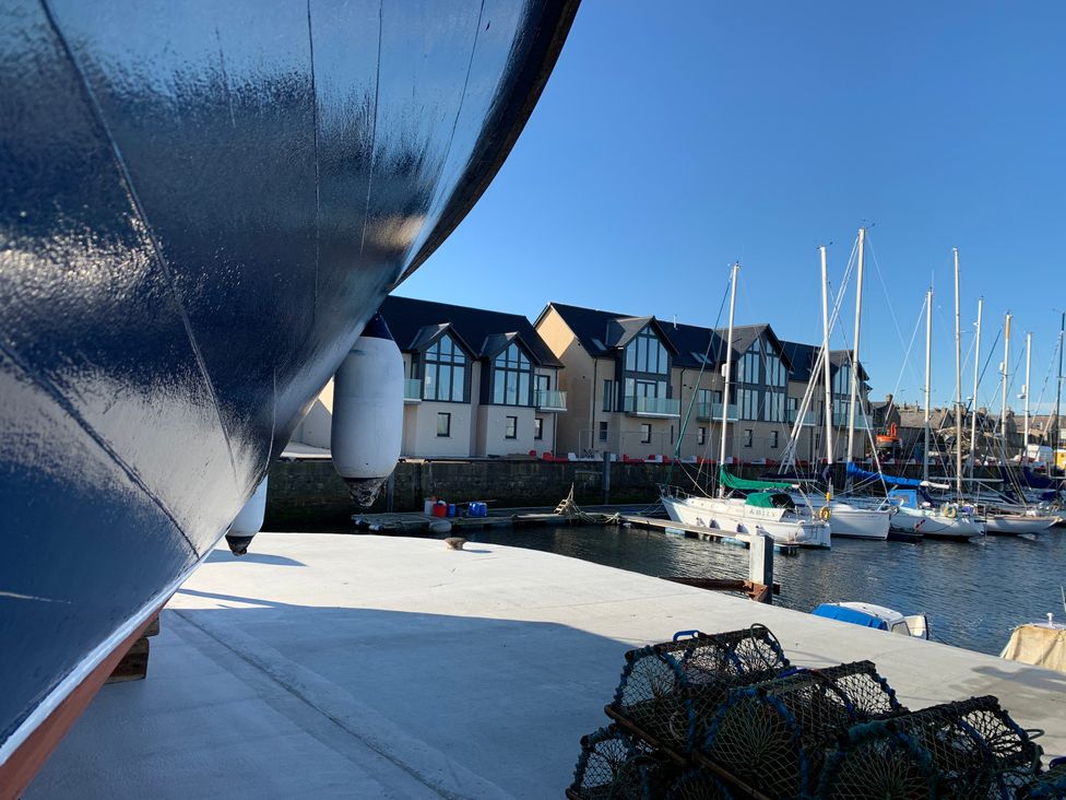 A marina with boats docked and modern buildings in the background at Spinnaker in Lossiemouth