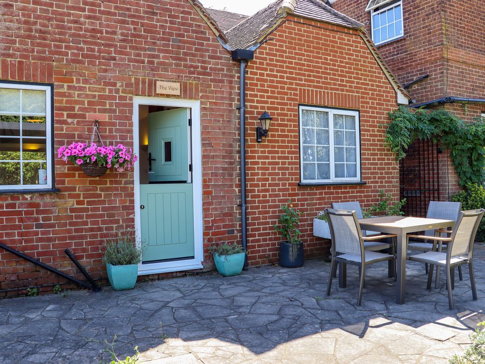 A patio area with a table and four chairs outside a brick building with a half-open door at The View in Goodnestone near Faversham