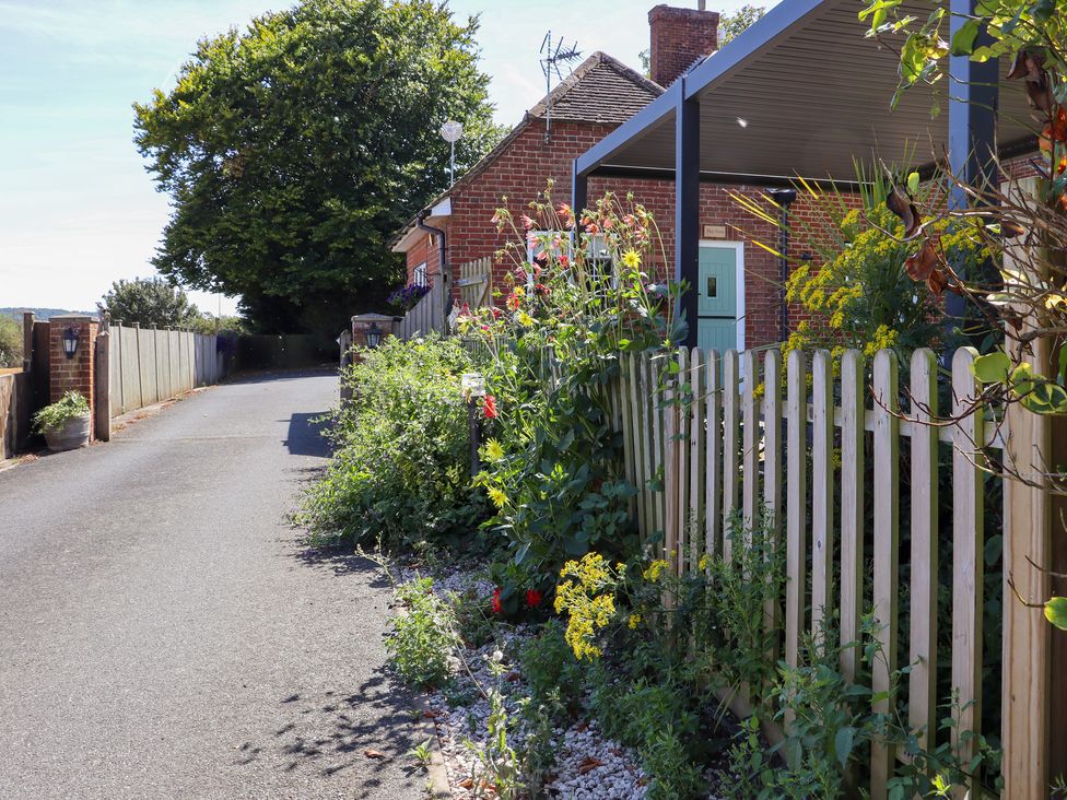 A pathway alongside a house with a wooden fence and garden plants at The View in Goodnestone near Faversham
