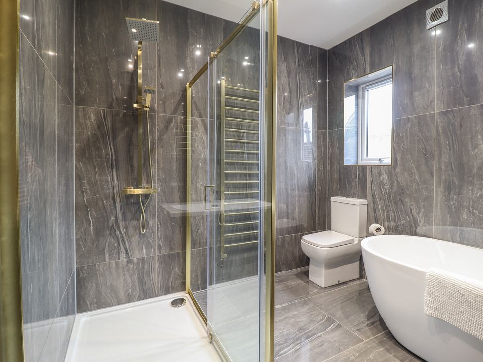 A bathroom with a shower enclosure a toilet a freestanding bathtub and a window at Gwydyr Bach 1 in Llanrwst