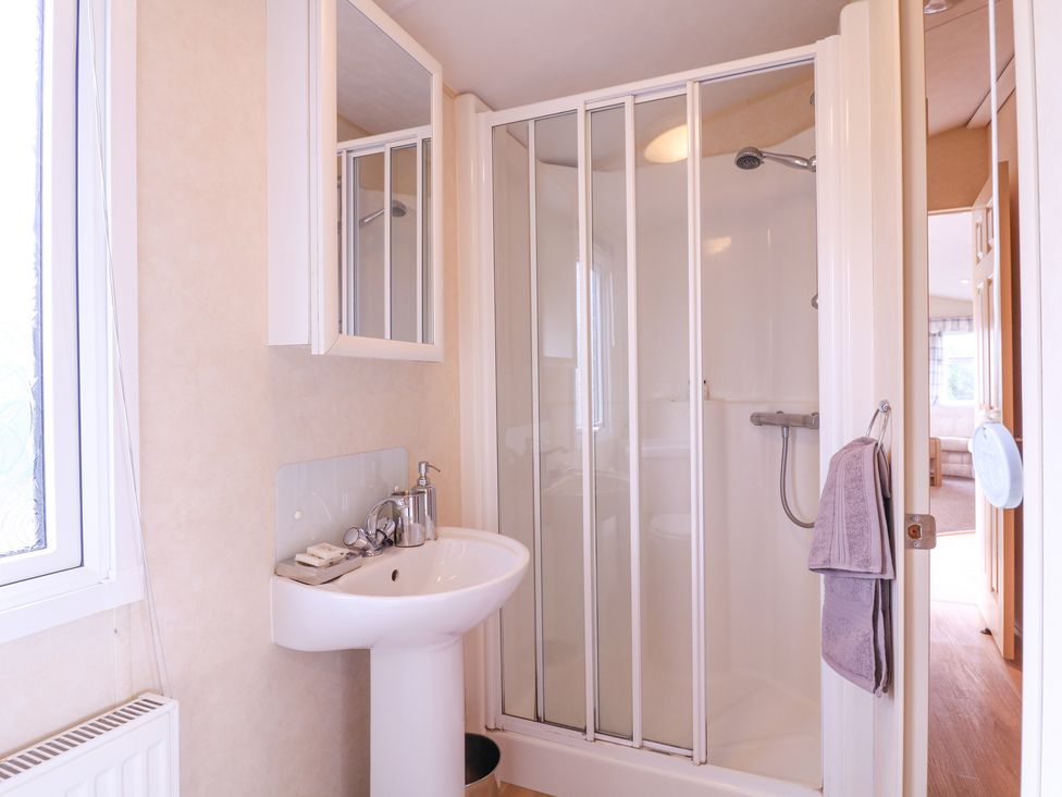 A bathroom with a pedestal sink mirror medicine cabinet and shower enclosure with sliding doors at The Richmond in St Osyth