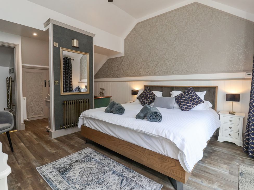 A bedroom with a large bed multiple pillows bedside tables and a mirror on the wall at Waters Edge Lock View in Gargrave