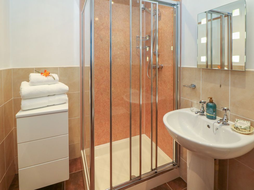 A bathroom with a shower cubicle towels on a cabinet and a sink at Temperance Croft in Wadshelf near Chesterfield