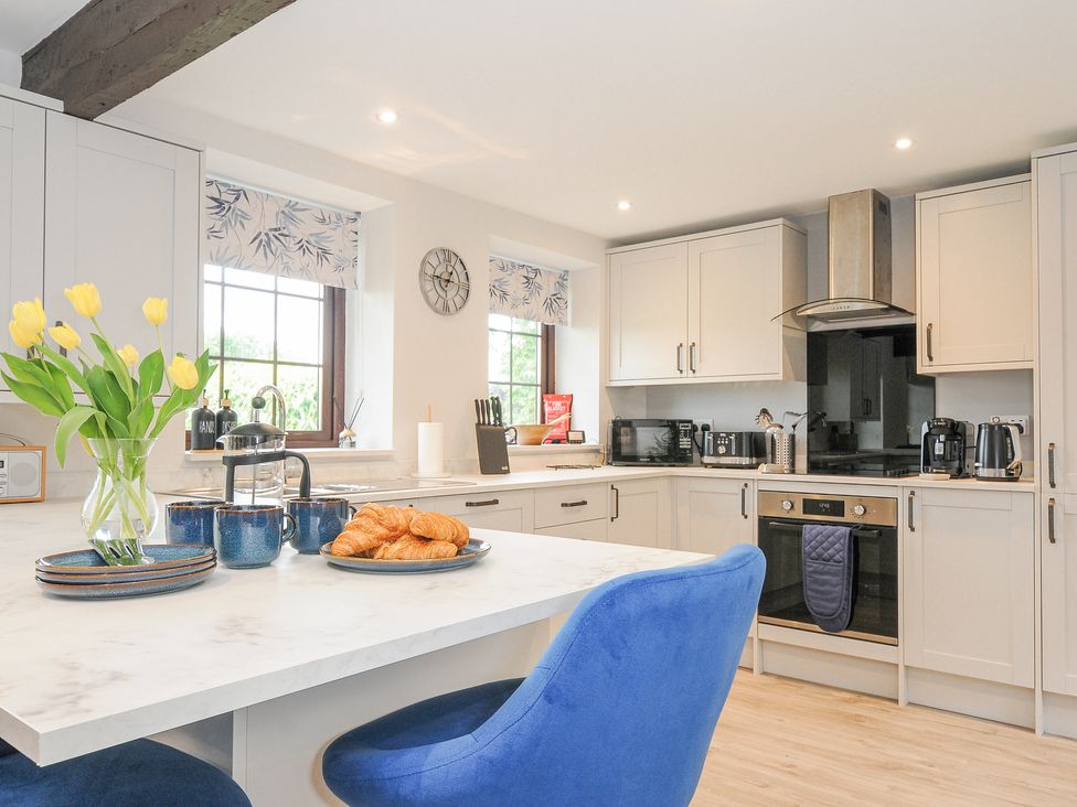 A kitchen with blue chairs yellow flowers croissants and appliances at Manor Barn in Saltash