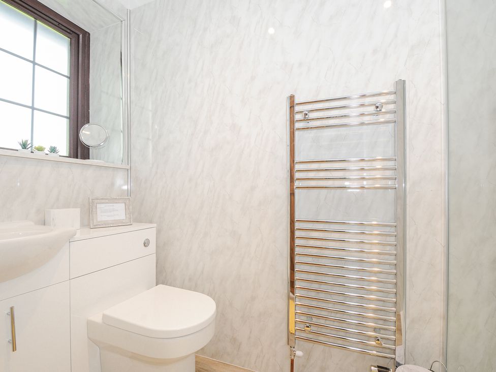 A bathroom with a toilet sink mirror window and chrome towel radiator at Manor Barn in Saltash