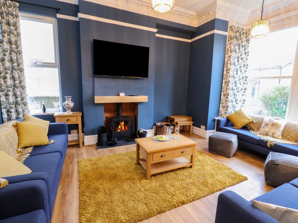 A living room with blue walls sofas and a wooden coffee table at Inglemead in Morecambe