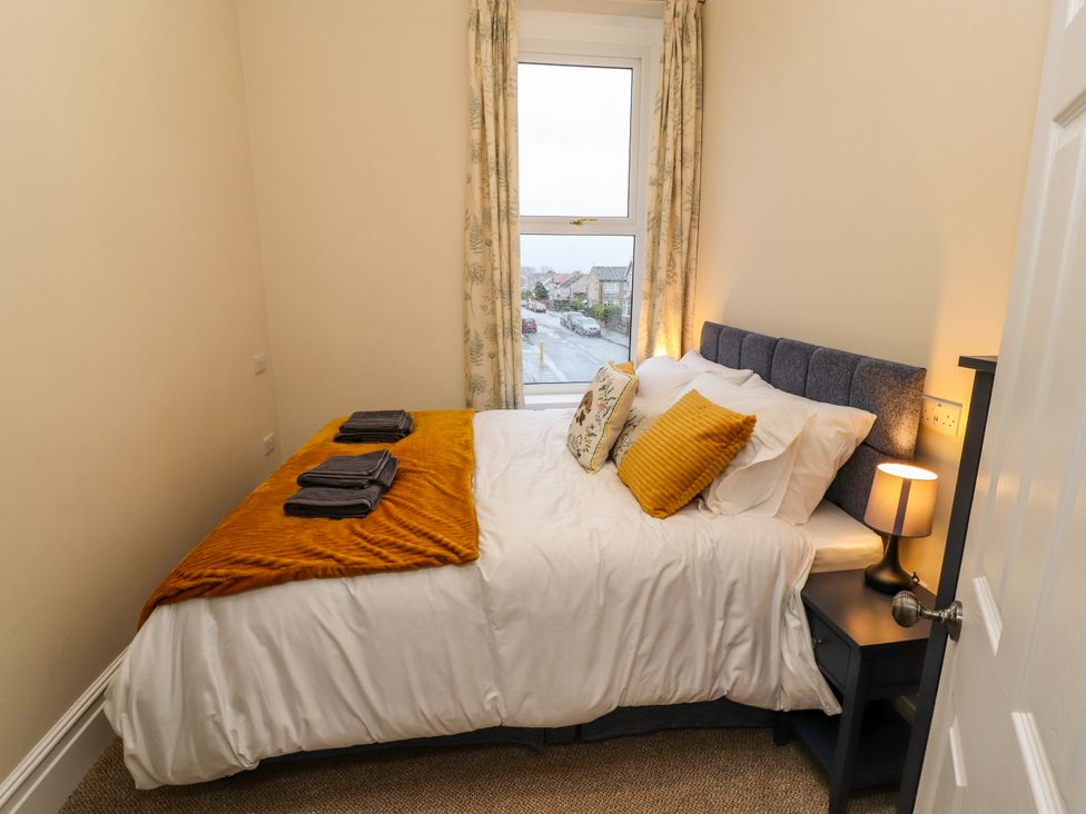 A bedroom with a bed pillows bedside table lamp and window at Inglemead in Morecambe