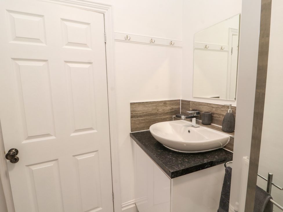 A bathroom sink with a mirror soap dispenser and toothbrush holder and a white door at Inglemead in Morecambe