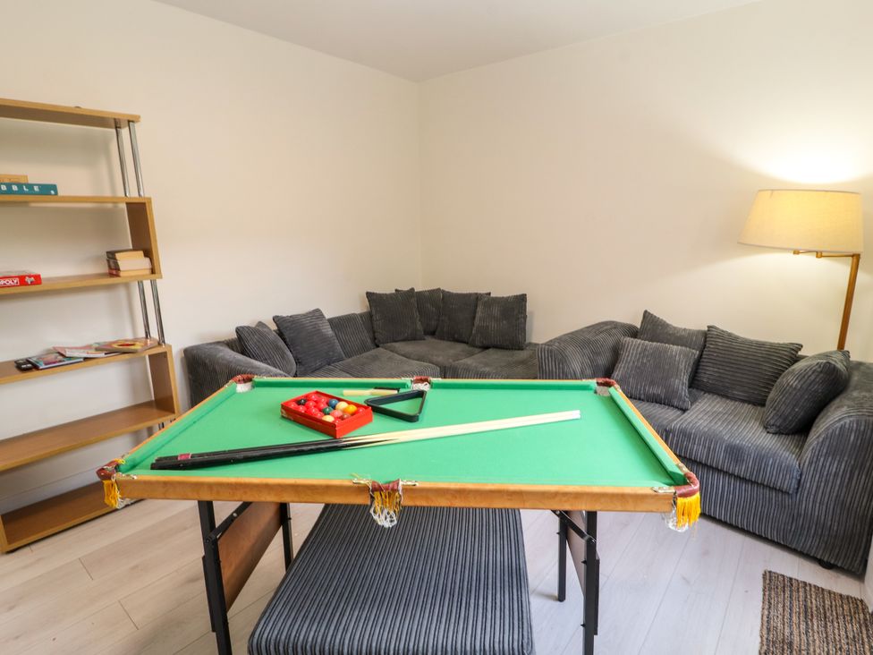 A living room with a pool table a grey sofa a floor lamp and a wooden shelving unit at Inglemead in Morecambe