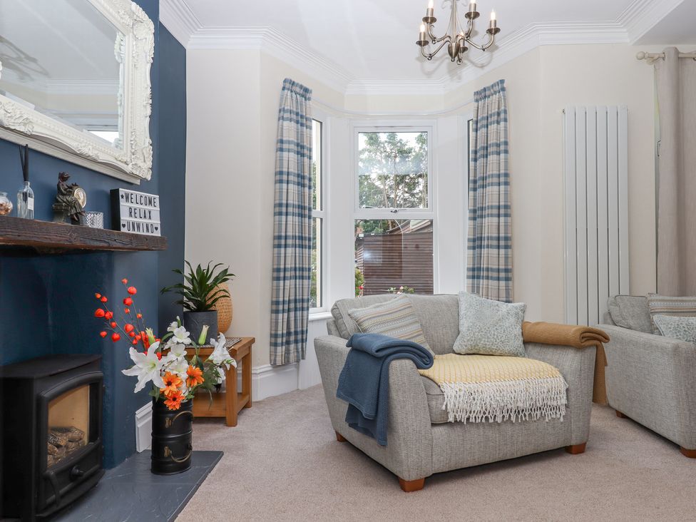 A living room with two armchairs a fireplace and a window with plaid curtains at Rockland House in Brixham