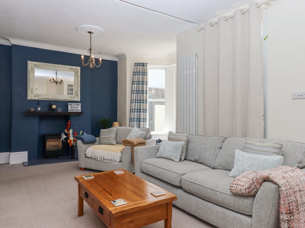 A living room with grey sofas a wooden coffee table and a fireplace with a mirror above at Rockland House in Brixham