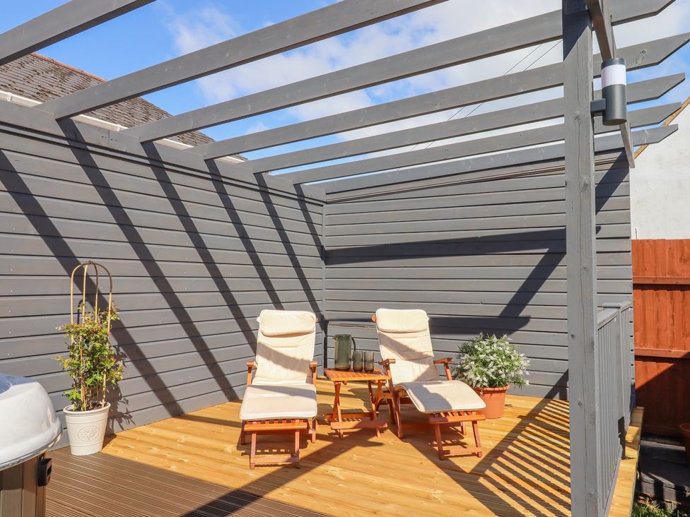 A wooden deck with two lounge chairs a small table with glassware and potted plants at Rockland House in Brixham