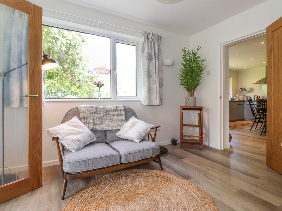 A sitting room with a gray sofa and cushions a round rug and a plant on a wooden stand at Sweden Bridge Cottage in Ambleside