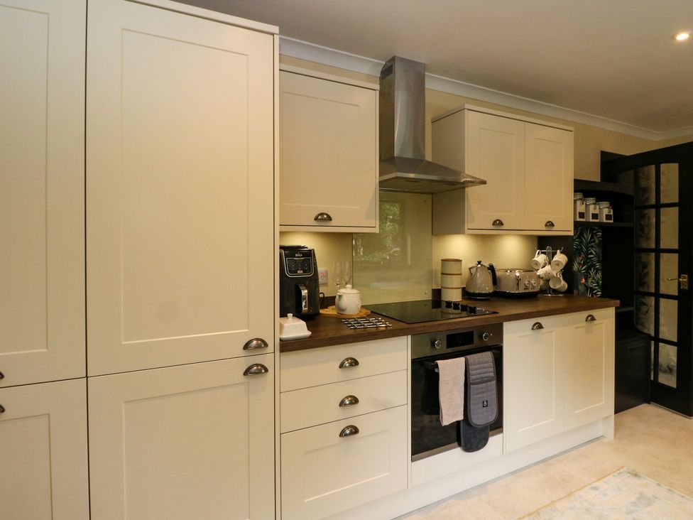 A kitchen with white cabinets wooden countertop appliances and a black door at Mo Dhachaidh in Roy Bridge
