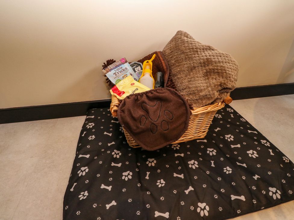 A wicker basket with pet supplies on a black mat with paw prints and bones at Mo Dhachaidh in Roy Bridge