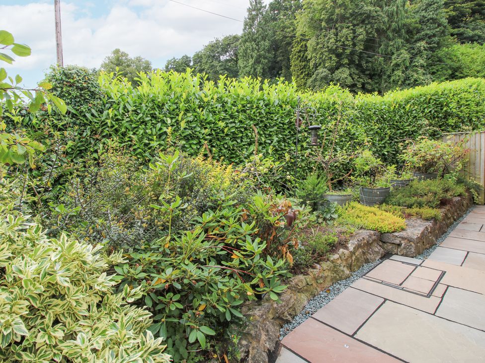 A garden with various plants and a stone border next to a paved walkway at 1 Church Street in Church Stretton