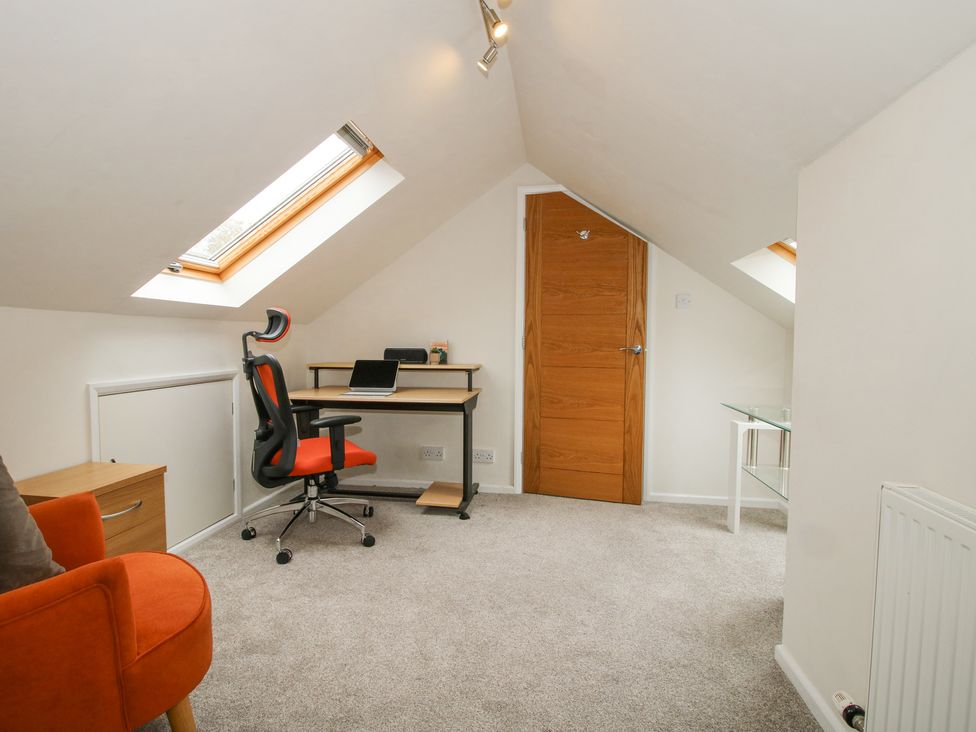 An attic office with a desk and chair skylights and an orange armchair at 1 Church Street in Church Stretton