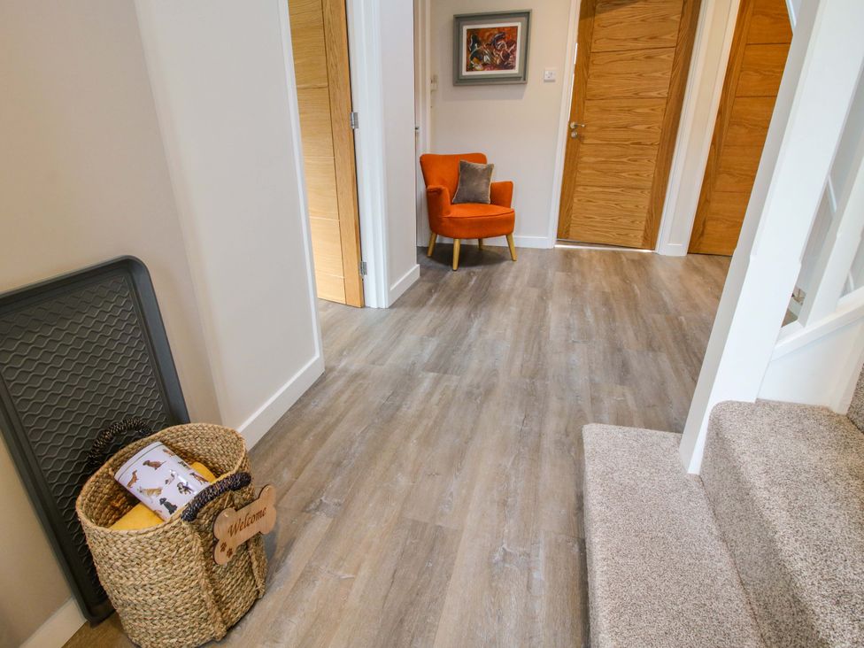 A hallway with wooden doors an orange armchair a basket and carpeted stairs at 1 Church Street in Church Stretton