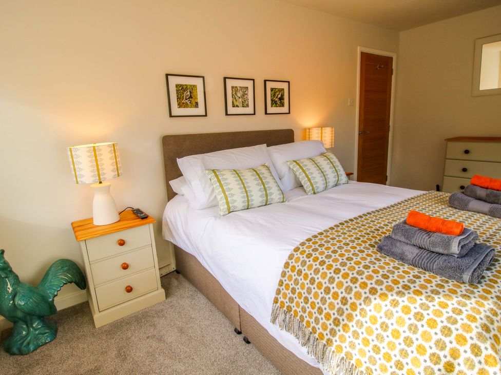 A bedroom with a bed with white linen and patterned throw and pillows bedside tables lamps and a green rooster statue at 1 Church Street in Church Stretton