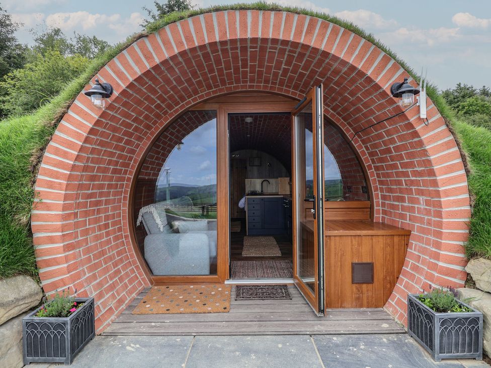 A round brick entrance with glass doors leading to a room with a sofa and kitchen at Rhosydd in Cyffylliog near Ruthin