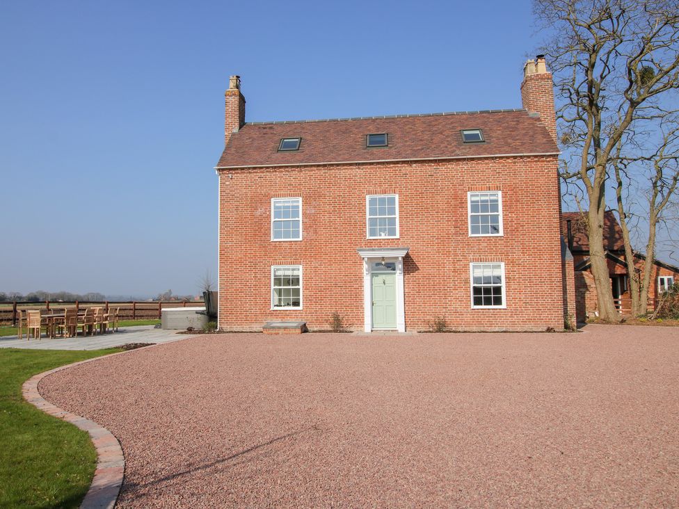 A brick farmhouse with a gravel driveway and outdoor dining area at Daniels Farmhouse in Claines
