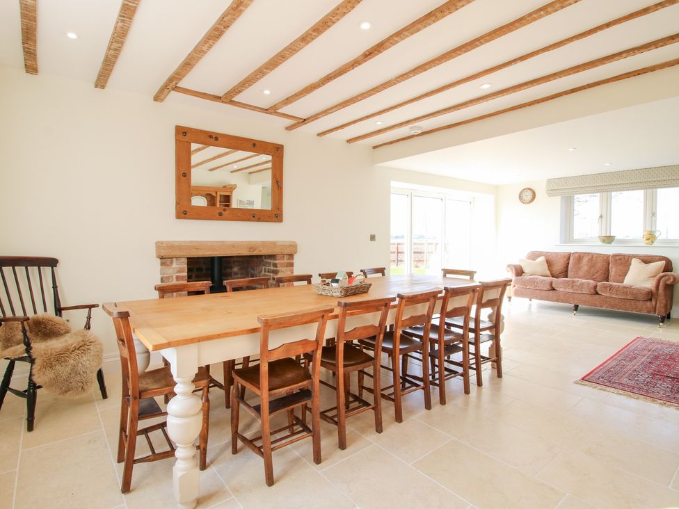 A dining area with a long wooden table surrounded by chairs and a sofa by the window at Daniels Farmhouse in Claines
