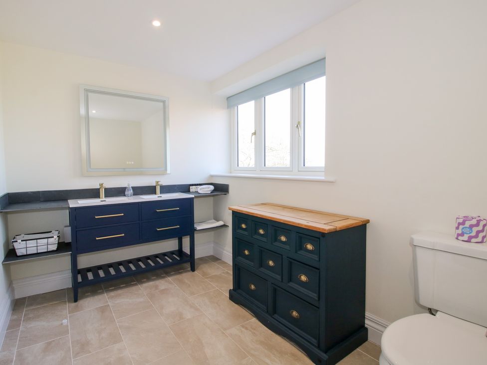 A bathroom with a double sink vanity, a chest of drawers, a toilet, and a window at Daniels Farmhouse in Claines
