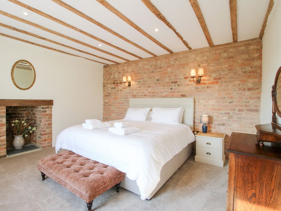 A bedroom with a bed and white bedding with a tufted bench at the end at Daniels Farmhouse in Claines