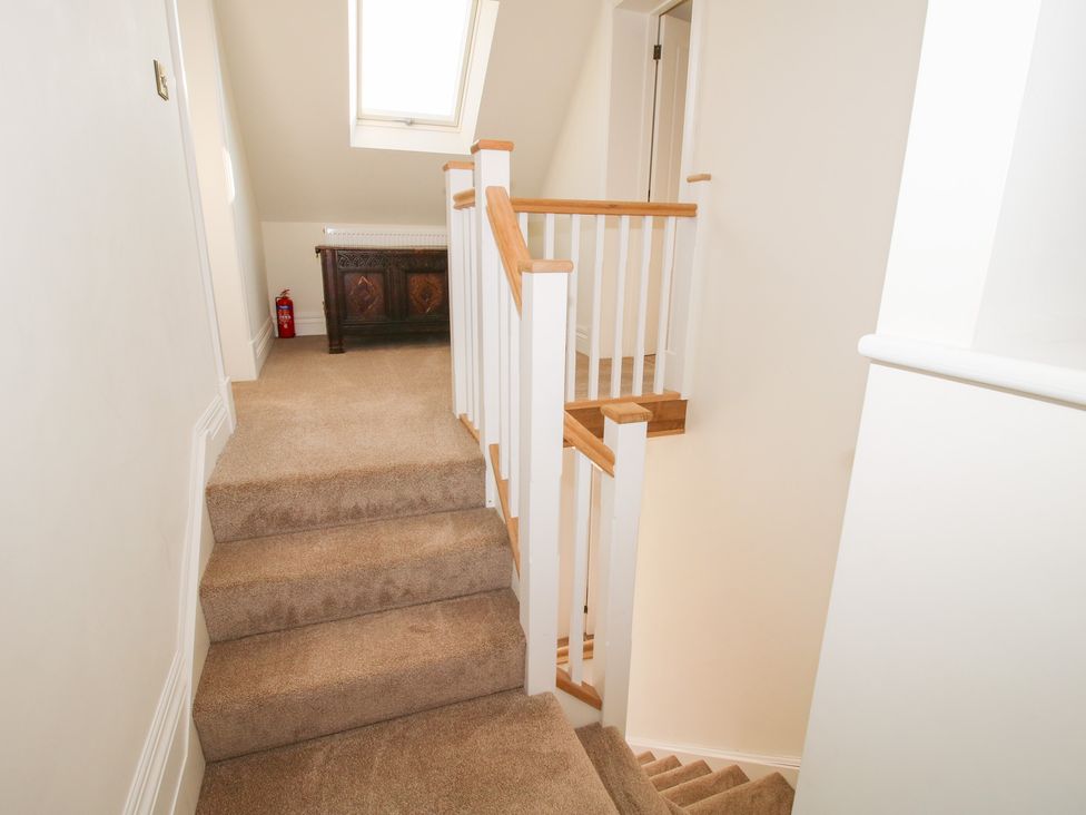 A carpeted staircase with white and wood railings and a wooden chest under a skylight window at Daniels Farmhouse in Claines