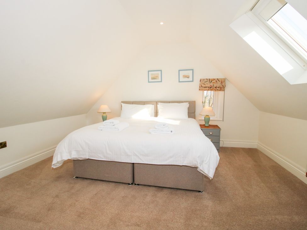 A bedroom with a bed bedside tables lamps and skylight window at Daniels Farmhouse in Claines