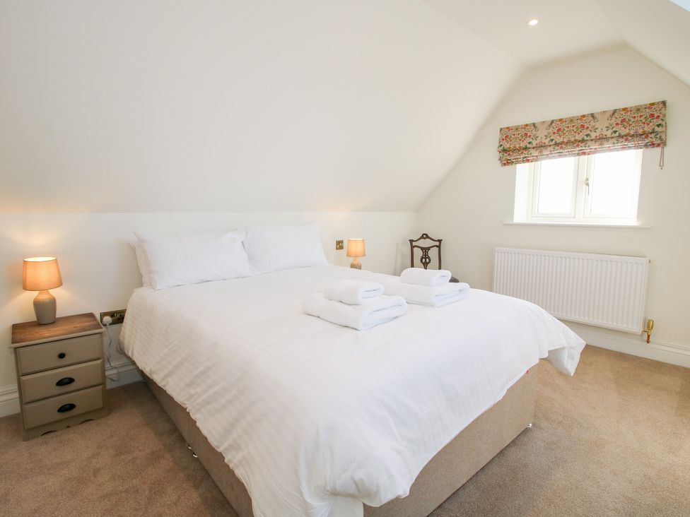 A bedroom with a white bedspread two bedside lamps a small window and a wooden chair at Daniels Farmhouse in Claines