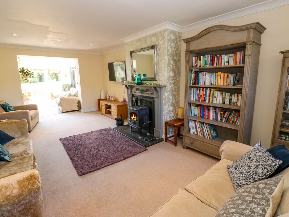 A living room with sofas a bookshelf a fireplace and a television at 14 Hill Close in Reeth
