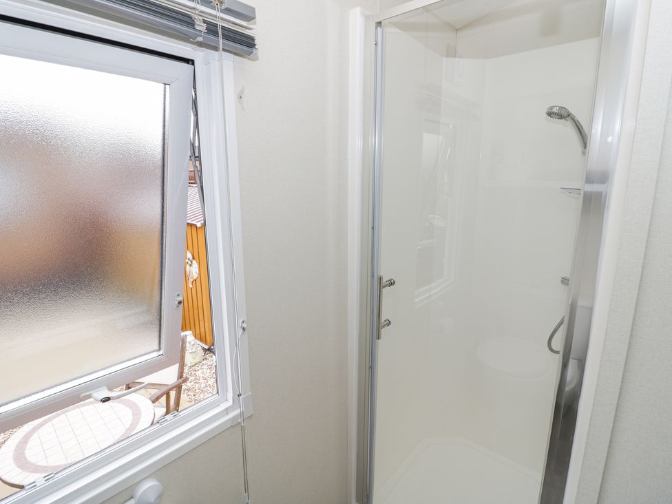 A bathroom with a shower enclosure and an open frosted window showing an outdoor table at Serenity in Wickhamford near Evesham