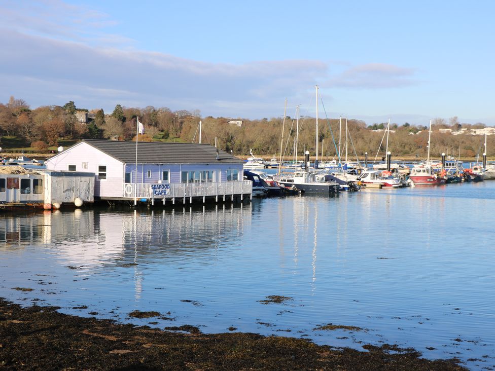 A pier with a seafood cafe and boats docked on a marina with trees in the background at Bay Cottage in Bembridge