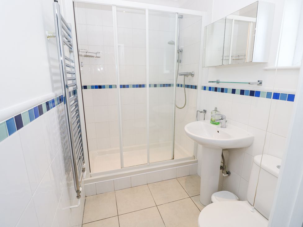 A bathroom with a shower enclosure sink toilet and a towel radiator at Bay Cottage in Bembridge