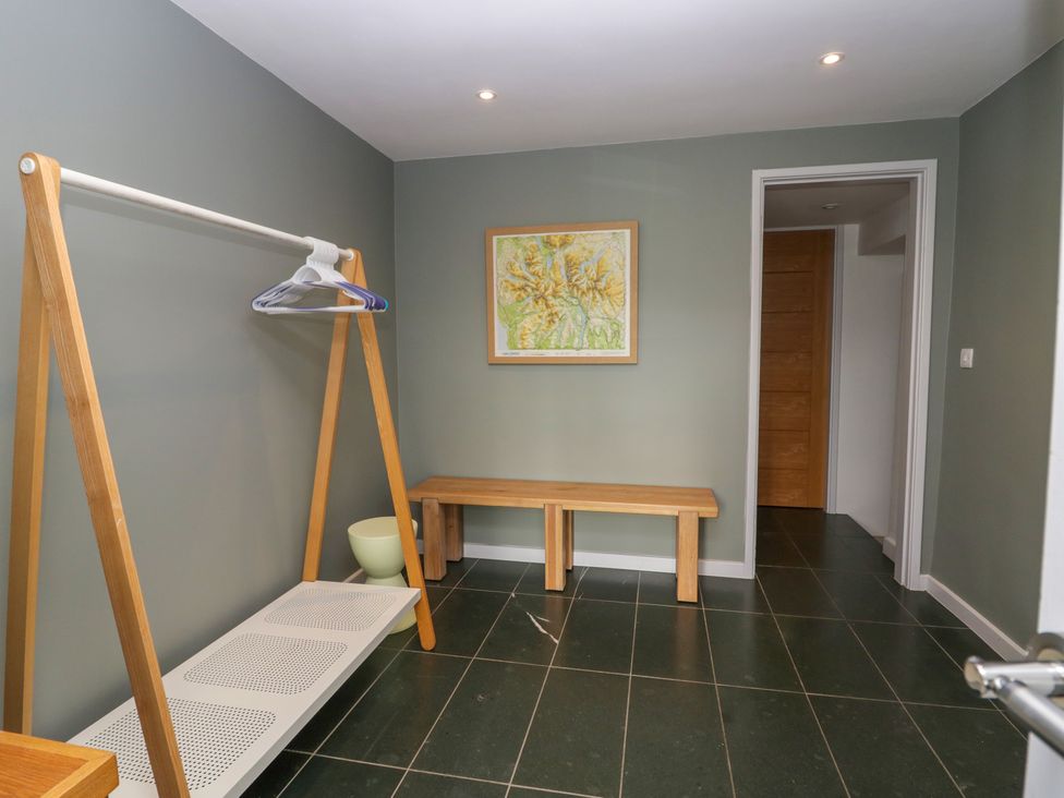 A room with a wooden bench a clothing rack with hangers a framed map on the wall and a tiled floor at Birkwray Barn Outgate near Hawkshead