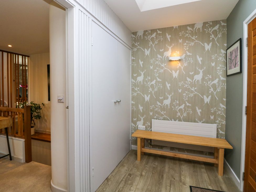 A hallway with a wooden bench against a wall with animal and bird wallpaper at Birkwray Barn in Outgate near Hawkshead