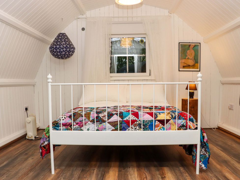A bedroom with a white metal bed frame and a multicolored quilt on the bed at Ballybeg Pod 7 Ballybeg near Tinahely County Wicklow